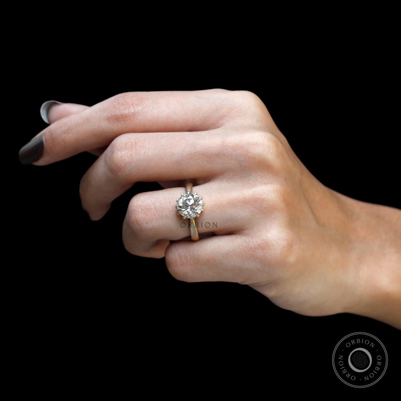 May include: A gold engagement ring with a large, round, clear diamond set in a halo setting.