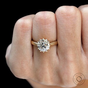 May include: A gold ring with a large, round, clear diamond set in a prong setting.