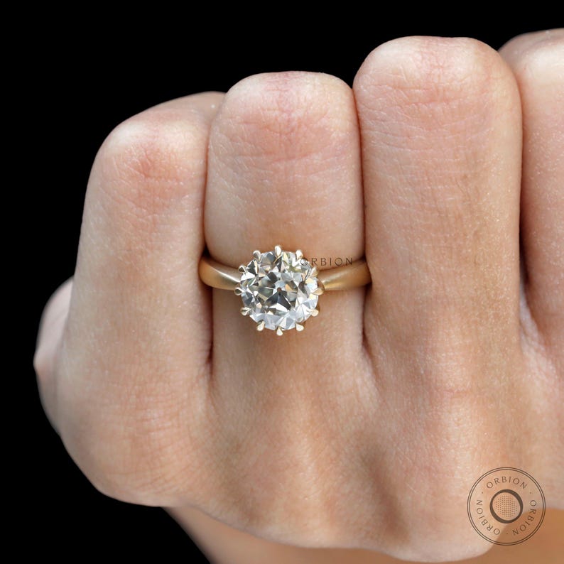 May include: A gold ring with a large, round, clear diamond set in a prong setting.