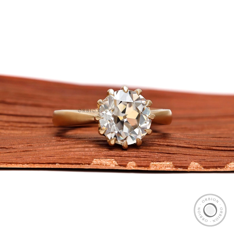 May include: A gold ring with a large, round, clear diamond. The diamond has a unique, faceted cut.