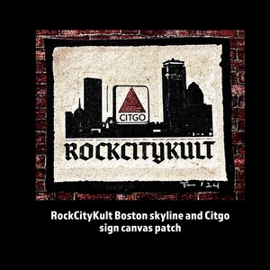 May include: A black and white illustration of the Boston skyline with the Citgo sign in the center. The text "RockCityKult" is written in a bold, gothic font below the skyline. The image is on a canvas patch with a brick background.