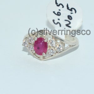 Pu&ograve; includere: Un anello d'argento con una pietra preziosa di rubino rosso e pietre bianche pi&ugrave; piccole. L'anello &egrave; taglia 6,5 ed &egrave; etichettato "No. 5".