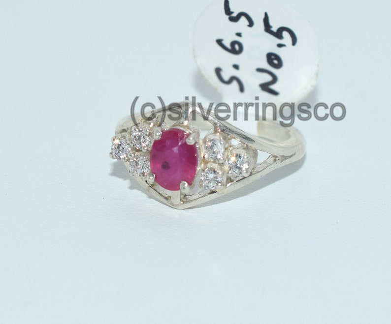 Pu&ograve; includere: Un anello d'argento con una pietra preziosa di rubino rosso e pietre bianche pi&ugrave; piccole. L'anello &egrave; taglia 6,5 ed &egrave; etichettato "No. 5".