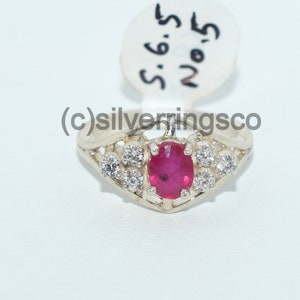 Pu&ograve; includere: Un anello d'argento con una pietra ovale rossa circondata da pietre pi&ugrave; piccole e trasparenti. L'anello &egrave; etichettato "S.6.5 No.5".