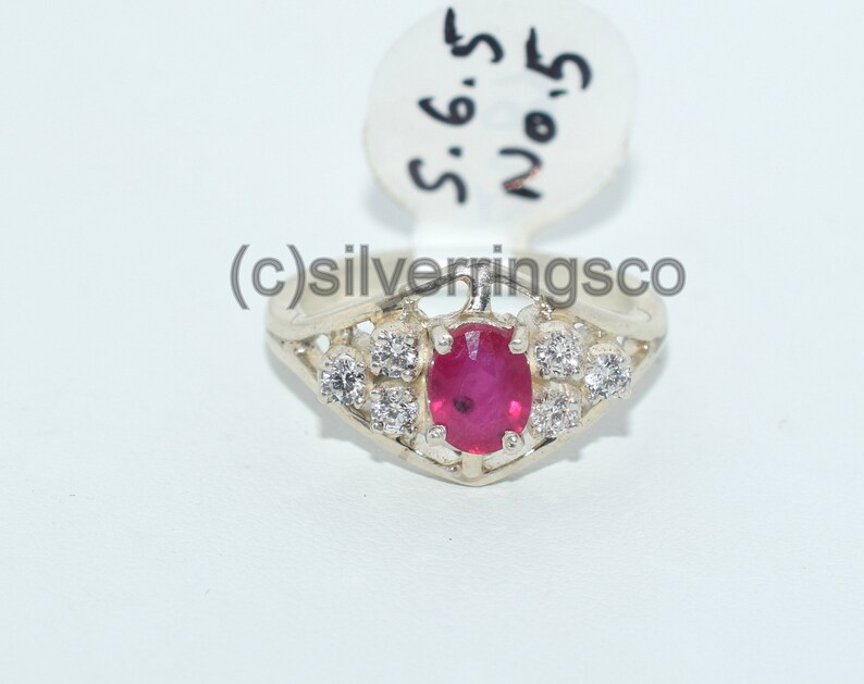 Pu&ograve; includere: Un anello d'argento con una pietra ovale rossa circondata da pietre pi&ugrave; piccole e trasparenti. L'anello &egrave; etichettato "S.6.5 No.5".