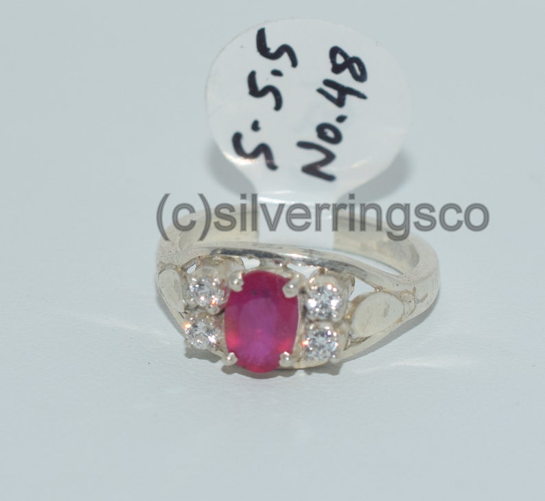 May include: A silver ring featuring a pink oval gemstone and smaller white gemstones. The ring is displayed on a white background with a tag labelled "S.S.S. No. 488".