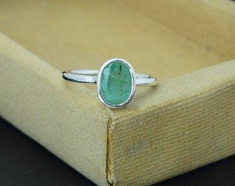 May include: A silver ring with a green oval emerald gemstone.