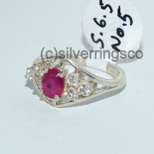 Pu&ograve; includere: Un anello d'argento con una pietra preziosa di rubino rosso e pietre di zircone cubico chiare. L'anello &egrave; taglia 6,5.