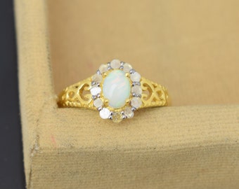 May include: A gold ring with an oval-shaped white opal gemstone surrounded by smaller clear gemstones.