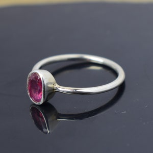 Puede incluir: Un anillo de plata con una piedra ovalada rosa. El anillo es simple y elegante.