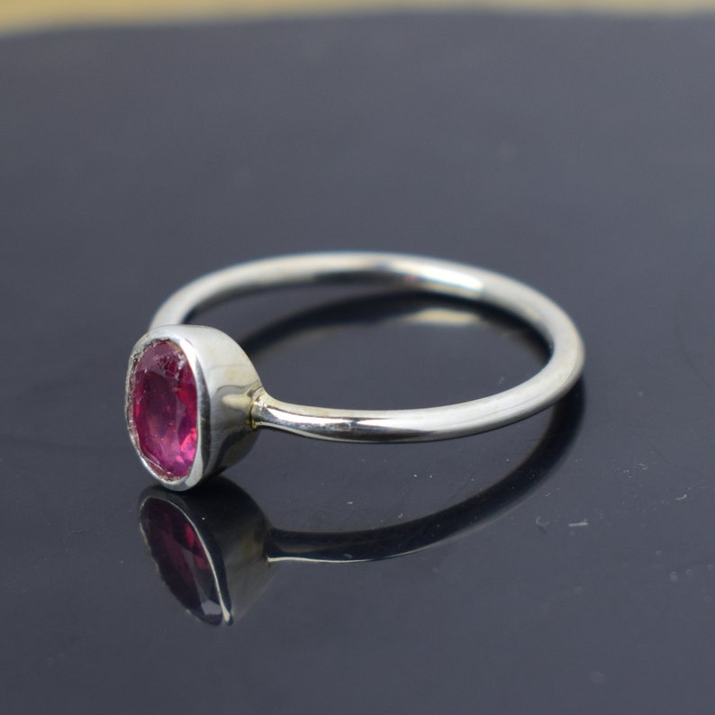Puede incluir: Un anillo de plata con una piedra ovalada rosa. El anillo es simple y elegante.
