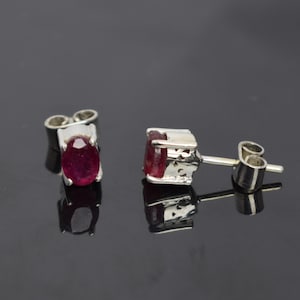 Puede incluir: Un par de pendientes de plata con piedras preciosas ovaladas rojas.