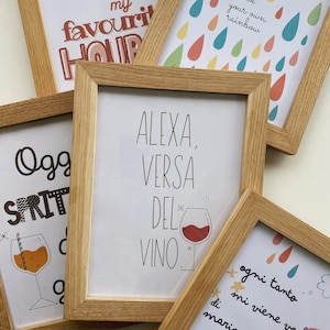 May include: Four framed prints with different designs. The top left print says "Happy Hour is my favorite hour". The top right print has a rainbow of raindrops with the text "Be your own rainbow". The bottom left print has a glass of a spritzer with the text "Oggi Spritz". The bottom right print has a glass of red wine with the text "Alexa, versa del vino".