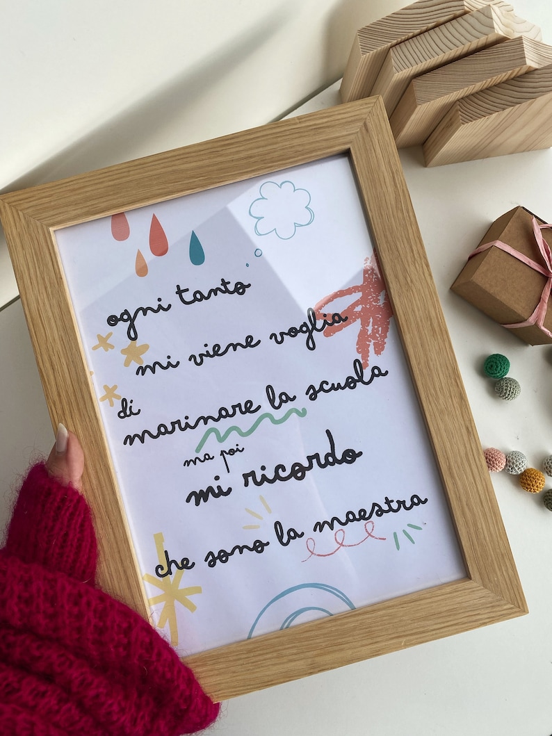 May include: A framed print with a white background and colorful illustrations. The text reads "ogni tanto mi viene voglia di marinare la scuola ma poi mi ricordo che sono la maestra".
