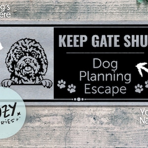 Puede incluir: Un letrero de metal negro y plateado con el texto "KEEP GATE SHUT" y "Dog Planning Escape". Una ilustración en blanco y negro de un perro asomándose por la parte superior del letrero. El letrero es para que un dueño de perro lo coloque en su puerta.