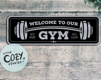 May include: Black and silver metal sign with the text "Welcome to our Gym No Pain No Gain" and a barbell with weights on each end.