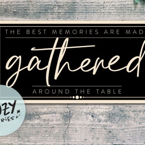 Może przedstawiać: Czarno-biały znak z tekstem "The best memories are made gathered around the table". Znak ma kremową ramkę i znajduje się na drewnianym tle.