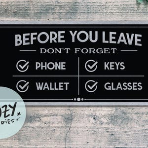 Puede incluir: Un letrero rectangular negro con texto blanco que dice "ANTES DE IRTE NO OLVIDES" seguido de "TELÉFONO", "LLAVES", "CARTERA" y "GAFAS". Un círculo azul claro con el texto "LITTLE COZY STORIES+" está en la esquina inferior izquierda.