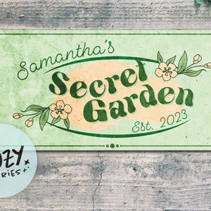 Könnte beinhalten: Ein grünes und weißes Schild mit dem Text "Samantha's Secret Garden Est. 2023" in einer Retro-Schrift. Das Schild hat eine pfirsichfarbene ovale Form mit grünen Blättern und weißen Blumen drumherum. Ein weißer Kreis mit dem Text "Little Cozy Stories+." befindet sich in der linken unteren Ecke des Bildes.
