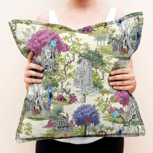 May include: A cream-coloured throw pillow with a colourful jungle scene featuring monkeys, temples, and lush foliage. The pillow has a pink, green, and blue colour scheme.