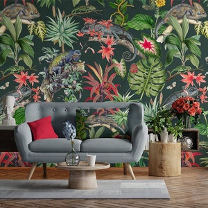 May include: A gray sofa with red and green patterned throw pillows in front of a dark green wallpaper with a tropical print featuring chameleons, flowers, and leaves.