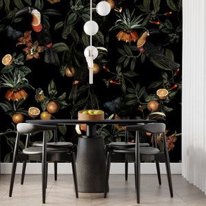 Pode incluir: Uma sala de jantar preta com uma mesa preta e quatro cadeiras pretas. A parede &eacute; coberta com um papel de parede floral escuro com tucans, borboletas e frutas c&iacute;tricas. Uma lumin&aacute;ria pendente preta fica pendurada acima da mesa.