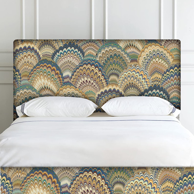 K&ouml;nnte beinhalten: Ein wei&szlig;es Bett mit einem gemusterten Kopfteil und Fu&szlig;teil. Das Kopfteil und das Fu&szlig;teil weisen ein wirbelndes, abstraktes Design in Blaut&ouml;nen, Gr&uuml;n, Gelb und Braun auf.