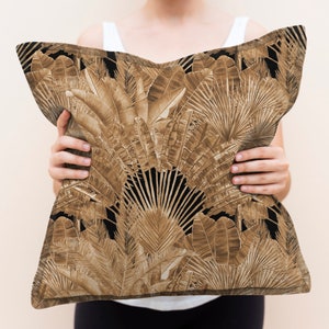 May include: A brown and black cushion with a tropical leaf pattern. The cushion is being held by a person.