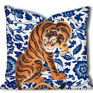 May include: A white throw pillow with a blue and white floral pattern and a large orange and black tiger illustration.