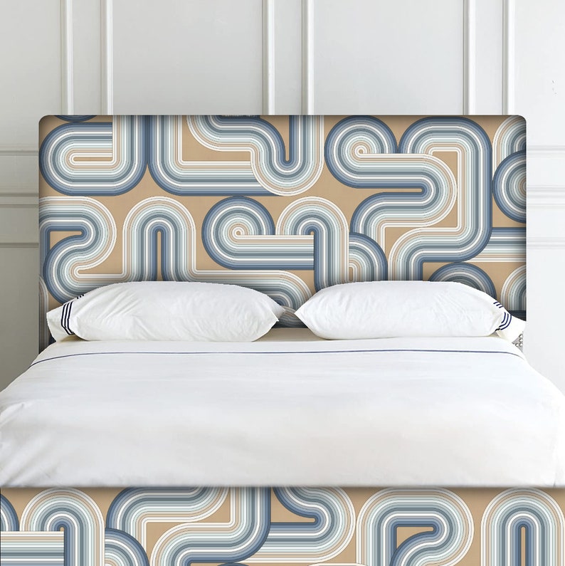 May include: A bed headboard featuring a geometric pattern of blue and beige curved lines. The headboard is made of fabric and has a modern design.