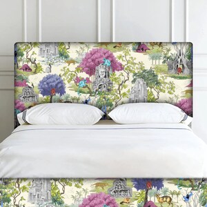 May include: A white bed with a patterned headboard featuring a jungle scene with pink trees, blue birds, and grey stone temples. The headboard is covered in a white fabric with a blue trim.