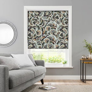 May include: A window with a patterned roman shade featuring a mushroom design in shades of brown, green, and white. The shade is raised, revealing a view of green foliage outside the window.
