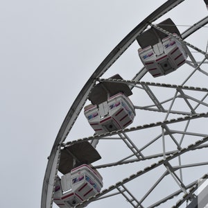 Peut inclure: Une grande roue blanche avec des accents rouges et bleus. La roue est en métal et possède une série de nacelles fermées.