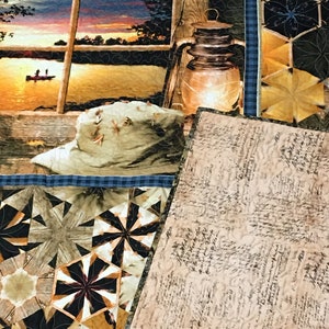 May include: A quilt with a patchwork design featuring a variety of geometric shapes in shades of brown, black, and gold. The quilt is folded in half, revealing a beige fabric with a handwritten script pattern.