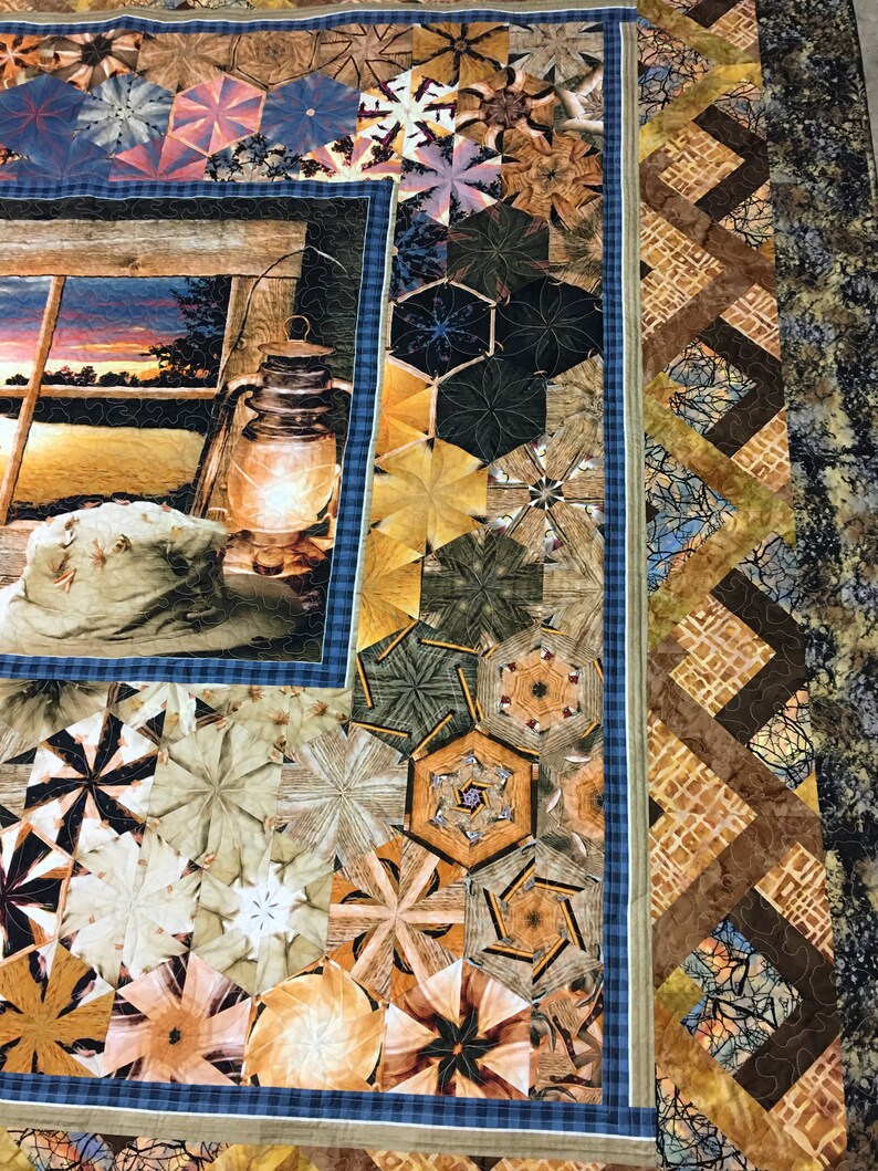 May include: A quilt with a patchwork design featuring a variety of geometric shapes and patterns in shades of brown, beige, and blue. The quilt has a border of brown and beige fabric with a geometric pattern. The quilt is made with a variety of fabrics, including cotton and linen.