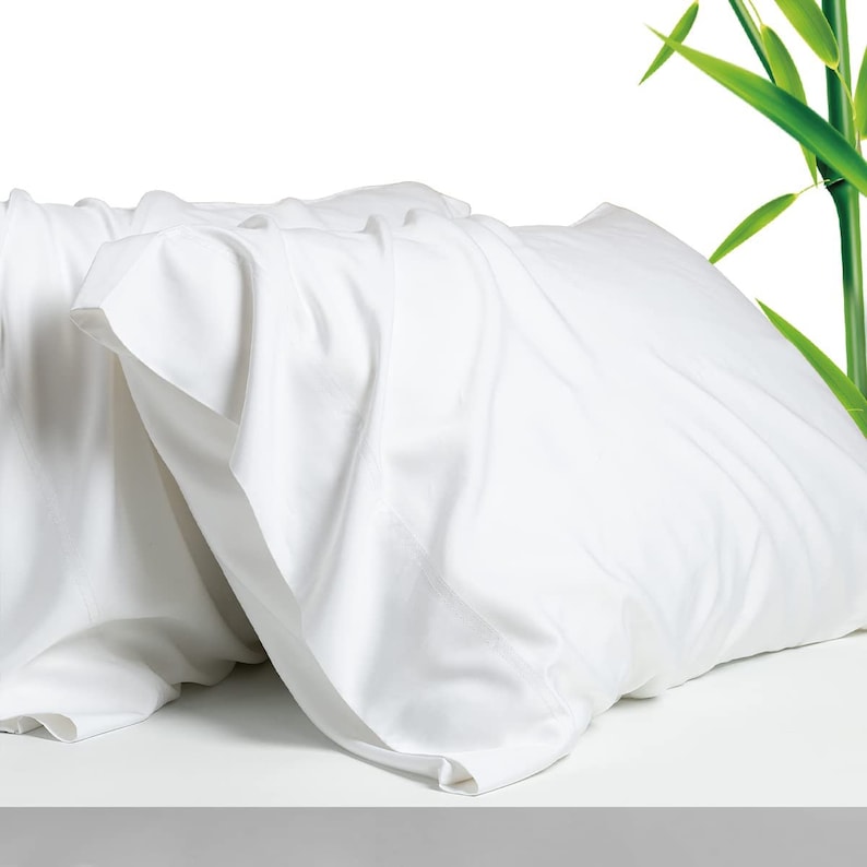 May include: Two white pillowcases made of soft, wrinkle-resistant bamboo fabric. The pillowcases are folded and arranged on a white surface.