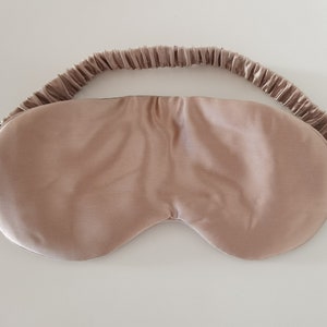 May include: A light brown silk sleep mask with a gathered elastic band.