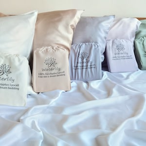 May include: A set of six pillowcases in various colors, including white, beige, light purple, light blue, and green. Each pillowcase has a small pouch with the text "Waterlily 100% Eucalyptus Lyocell Fine like a dream bedding" printed on it.