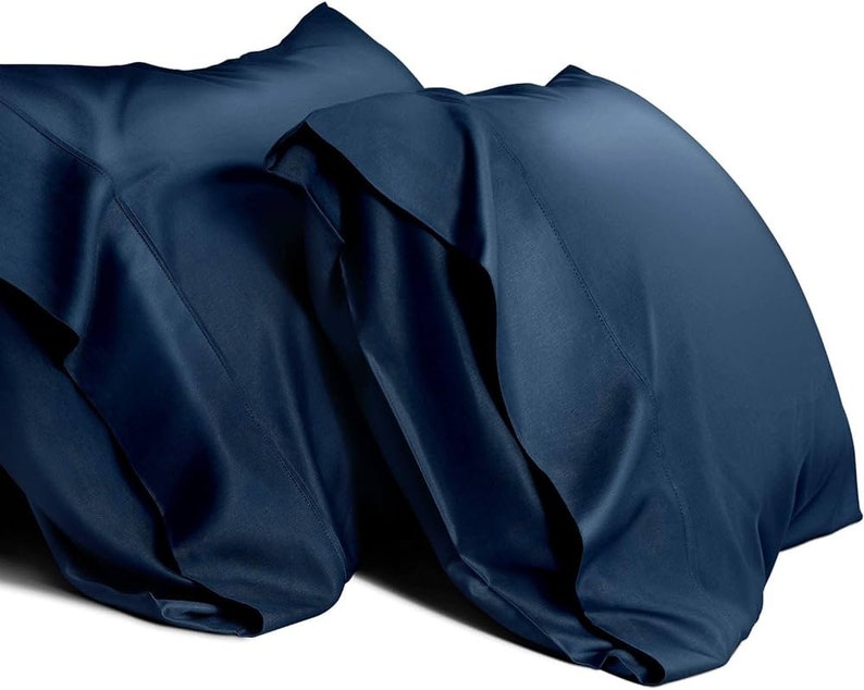 May include: Two dark blue pillowcases made of a soft, silky material. The pillowcases are folded and stacked on top of each other.