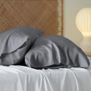 May include: Two gray satin pillowcases on a white bed. The pillowcases are smooth and wrinkle-free.