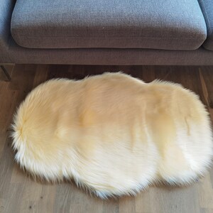 May include: A fluffy, cream-colored faux fur rug with a soft, shaggy texture.