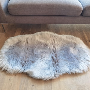 May include: A fluffy gray faux fur rug on a wooden floor.