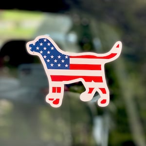 Könnte beinhalten: Eine weiße Silhouette eines Hundes mit dem Design der amerikanischen Flagge. Der Hund blickt nach rechts und hat seinen Schwanz eingerollt.