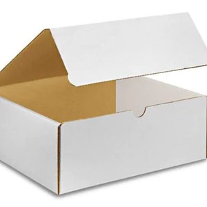 May include: A white cardboard box with a flap open, revealing the inside of the box. The box is made of sturdy cardboard and has a smooth, white finish.