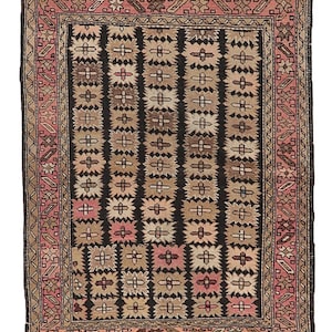 Puede incluir: Una alfombra vintage con un patrón geométrico en tonos marrones, rosas y negros. La alfombra tiene un campo central con un patrón repetitivo de cuadrados y rombos, rodeado por un borde con un diseño más intrincado.