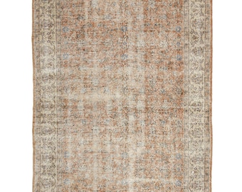 May include: Rectangular, distressed rug with a central field of faded orange and beige tones. The rug features a detailed border with floral and geometric patterns in beige, blue, and brown. The rug's design suggests a vintage or antique style.