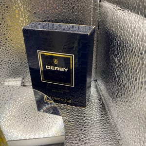 May include: A navy blue box of Derby by Guerlain aftershave. The box has gold lettering and a gold border. The text on the box reads "AFTER SHAVE lotion apr&egrave;s rasage, parfum&eacute;e" and "1.7 fl. oz. N&deg; 762".