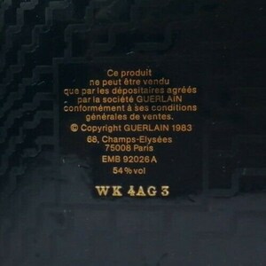 May include: A dark background with a rectangular label featuring gold text. The text includes the phrase "Ce produit ne peut &ecirc;tre vendu" and "Copyright GUERLAIN 1983". Additional text includes the address "68, Champs-Elys&eacute;es, 75008 Paris" and "54% vol".