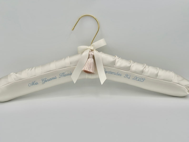 ivory satin hanger with gold neck, personalized with blue embroidery, ivory tassel and bow, theboondockquiltco hanger tag