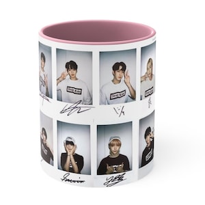 May include: White ceramic mug with a pink interior. The exterior features a collage of photos of a group of people, with the text "Stray Kids" on their shirts. The mug is decorated with signatures.